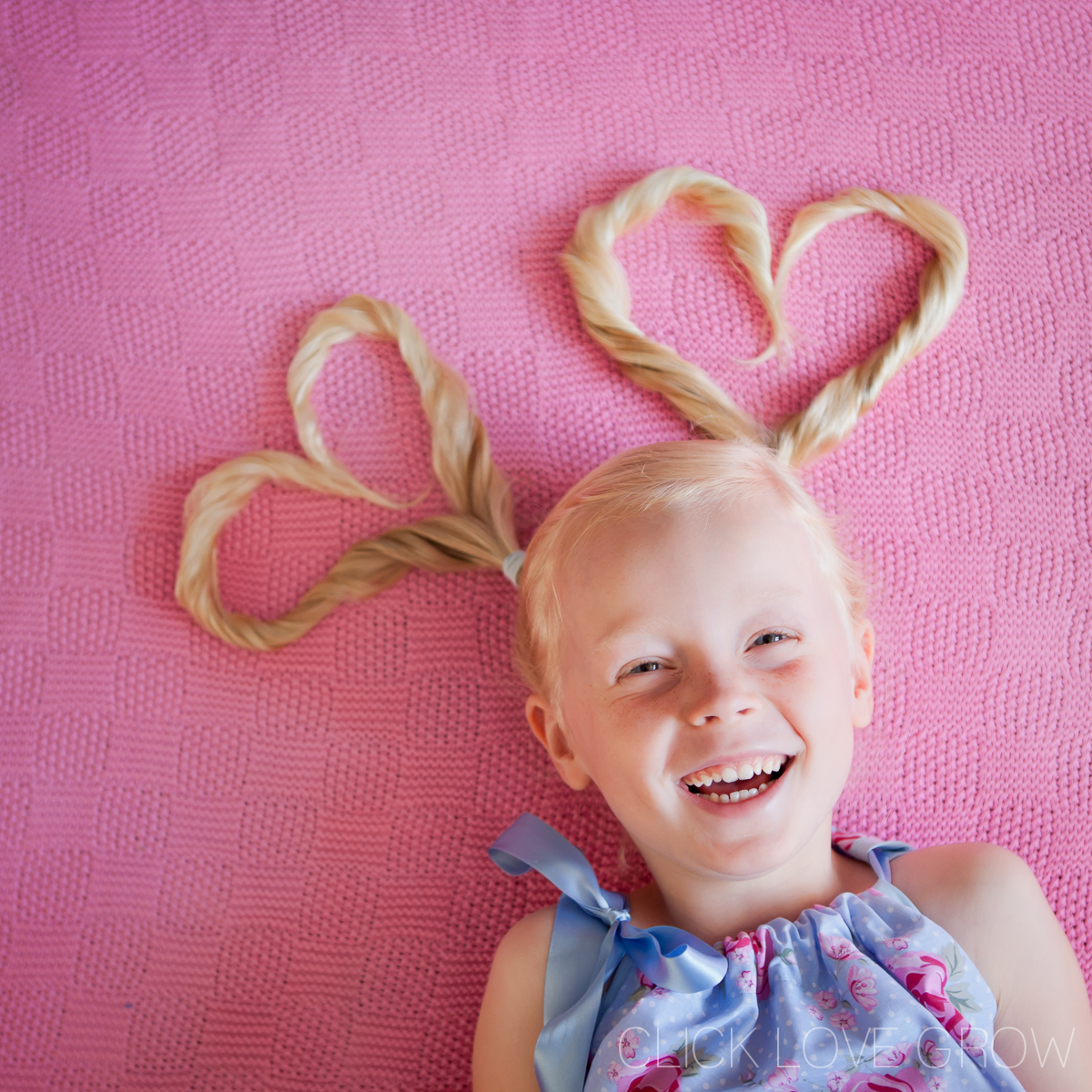 little girl with hair arranged like hearts smiling for the shot