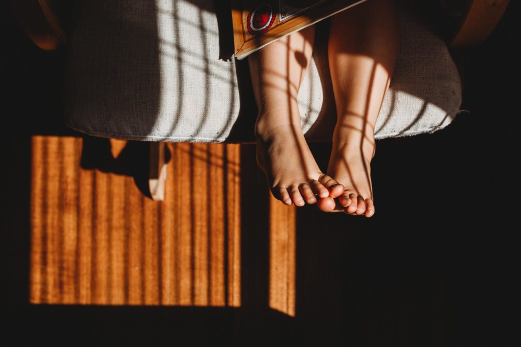 dramatic light photos feet hanging off chair with shadows