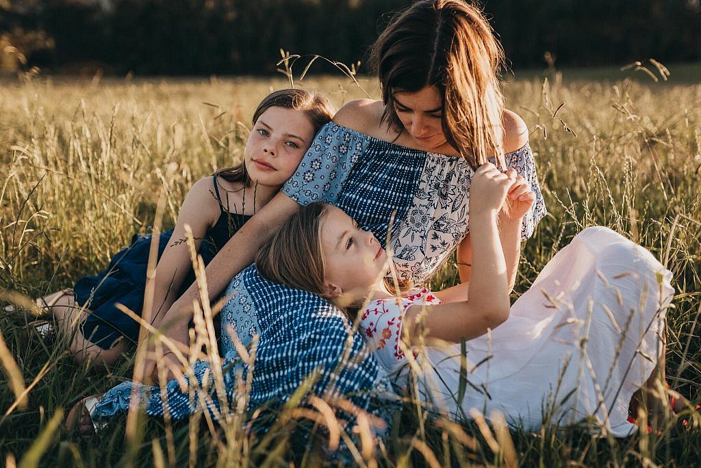 mother sitting with daughters in field