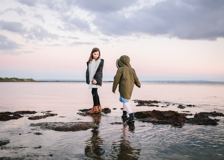 two girls walking on the shore