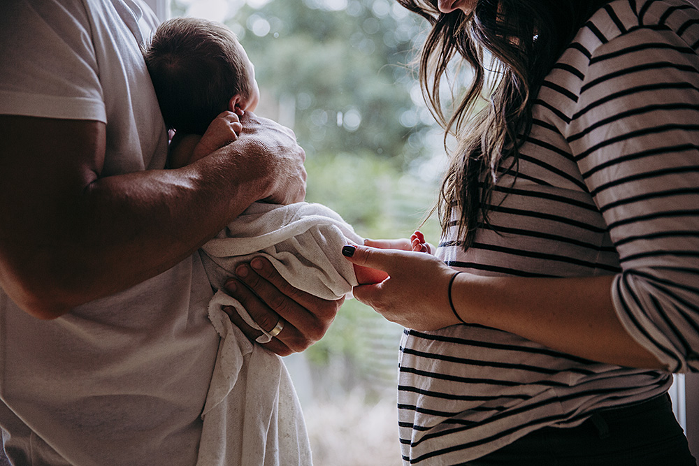 parents with newborn baby holding his feet
