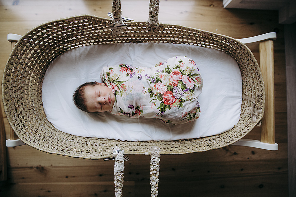 baby wrapped sleeping in bassinet under soft light