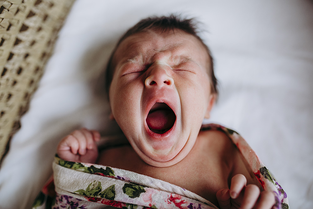 newborn yawning wrapped inside bassinet
