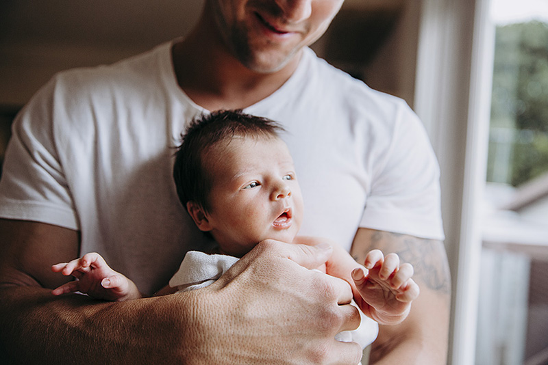 lifestyle pictures of father holding newborn