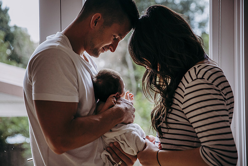 low light lifestyle pictures of parents holding newborn