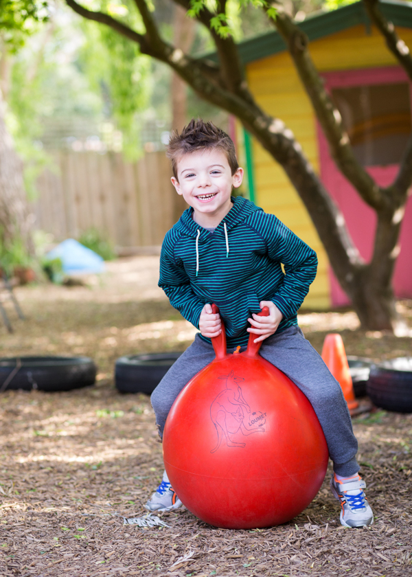 little boy riding a red ball