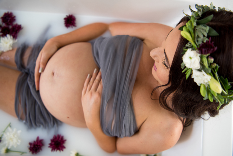 woman holding her bump during milk bath maternity photo session