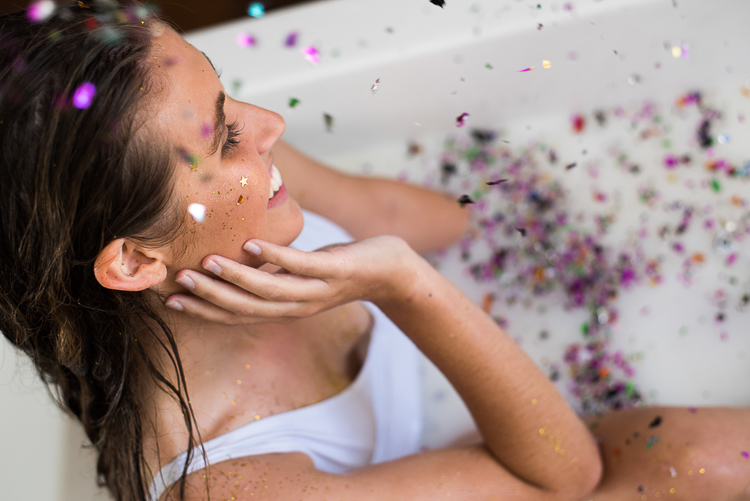 woman laughing with glitter during maternity milk bath photoshoot