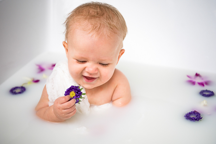 baby playing with flowers in milk bath maternity shoot
