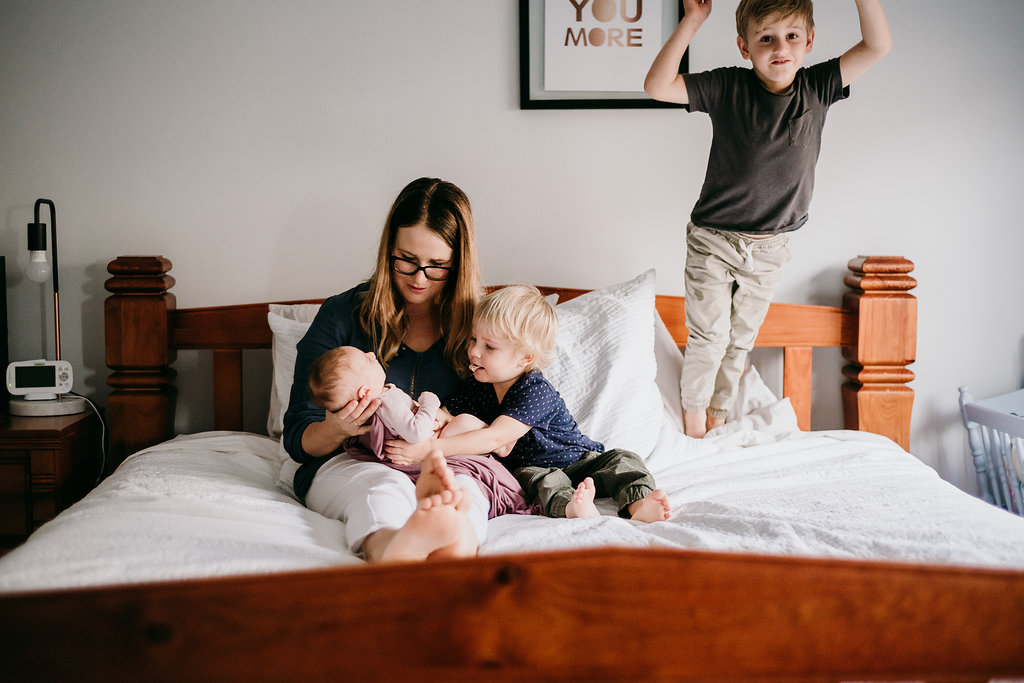 mother in bed with children and newborn