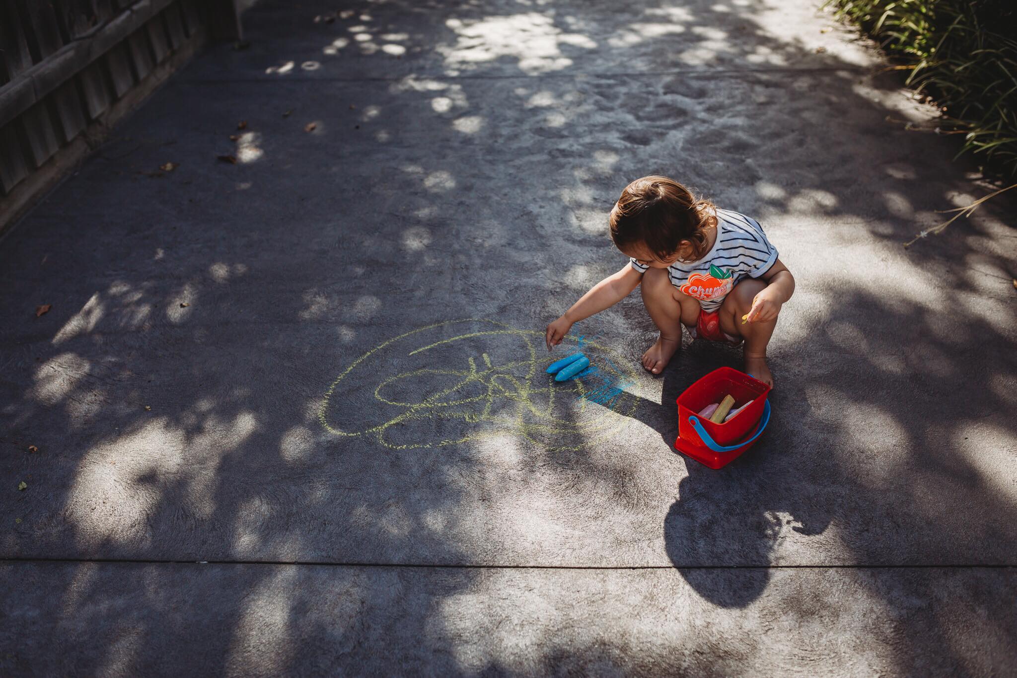 shadow photography of little girl drawing on the ground