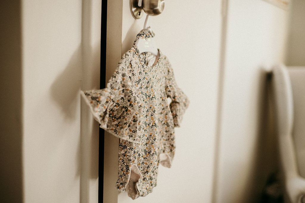 baby milestone photos of a floral baby dress on a hanger