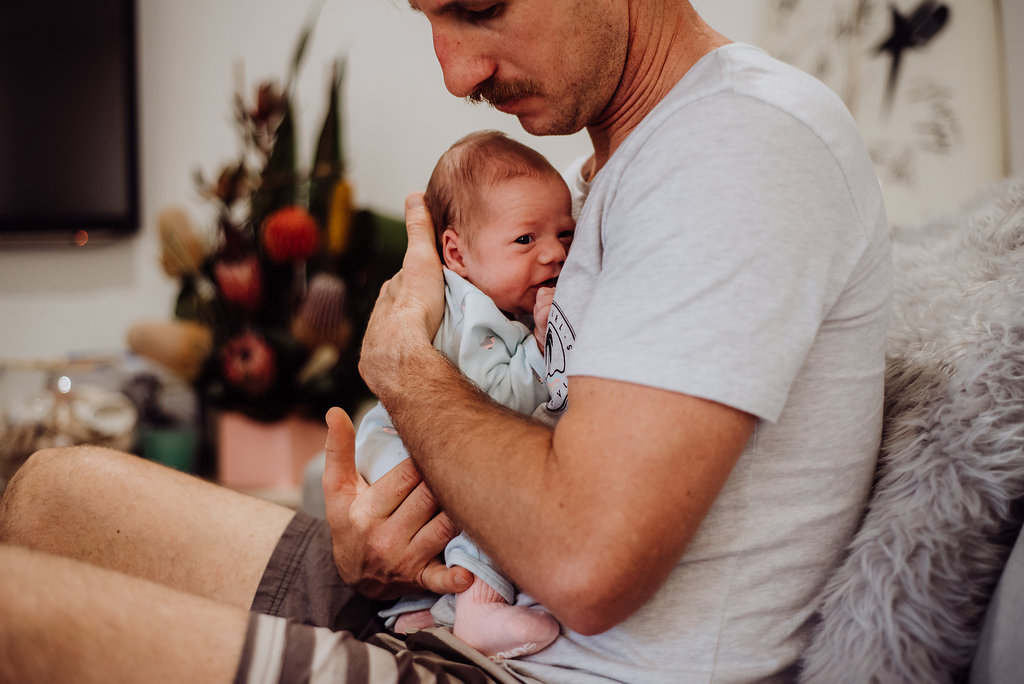 father holding newborn baby at chest