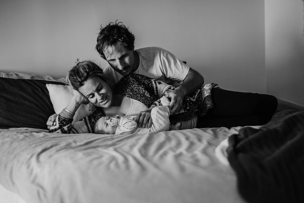 mother and father with newborn baby on bed