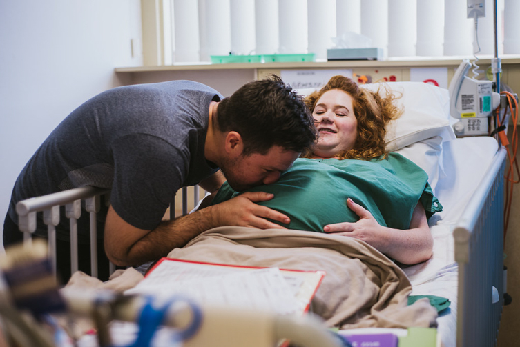 man kissing wife’s belly before birth