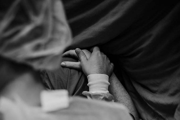 husband holding wife’s hand at birth