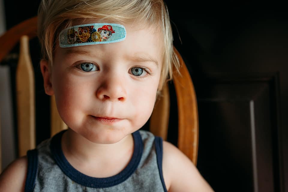shot of boy sitting with a band-aid on his face