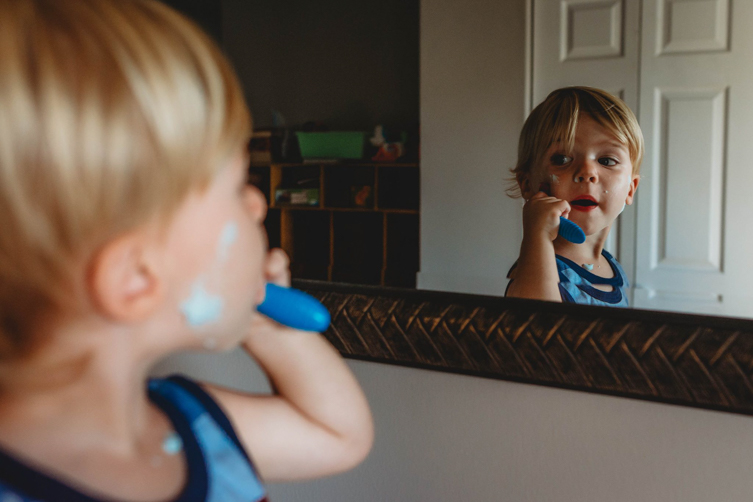 photography of boy shaving in front of mirror