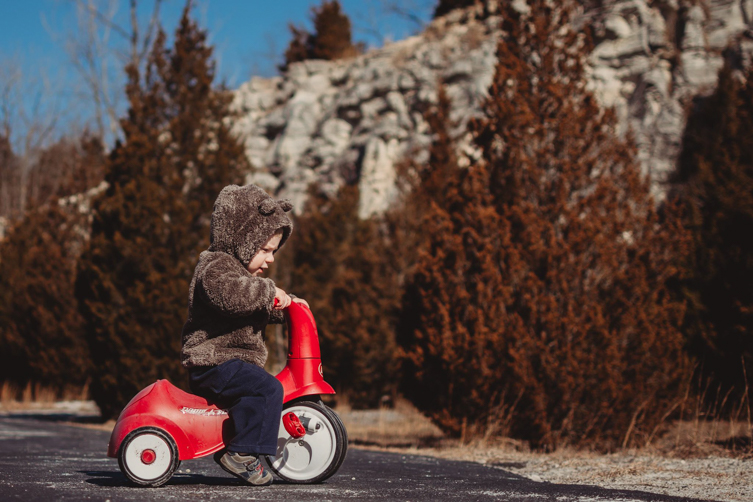 little boy riding red bike