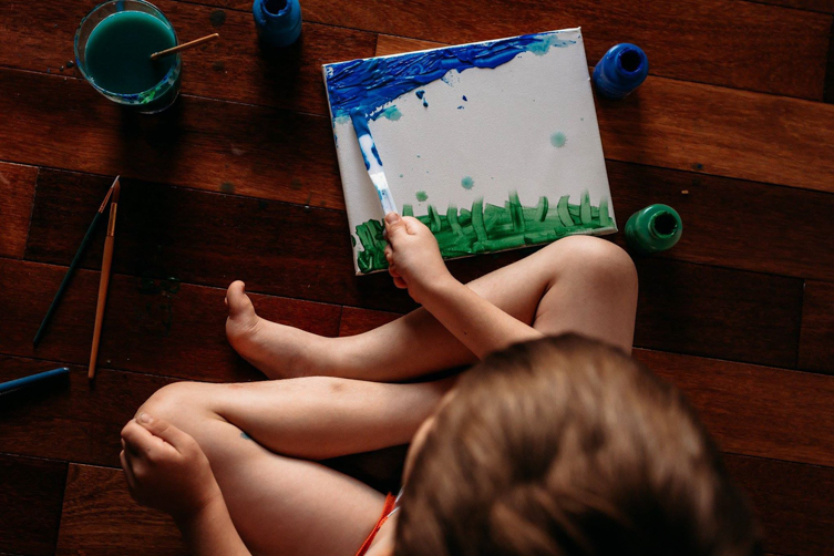 little boy painting in green and blue