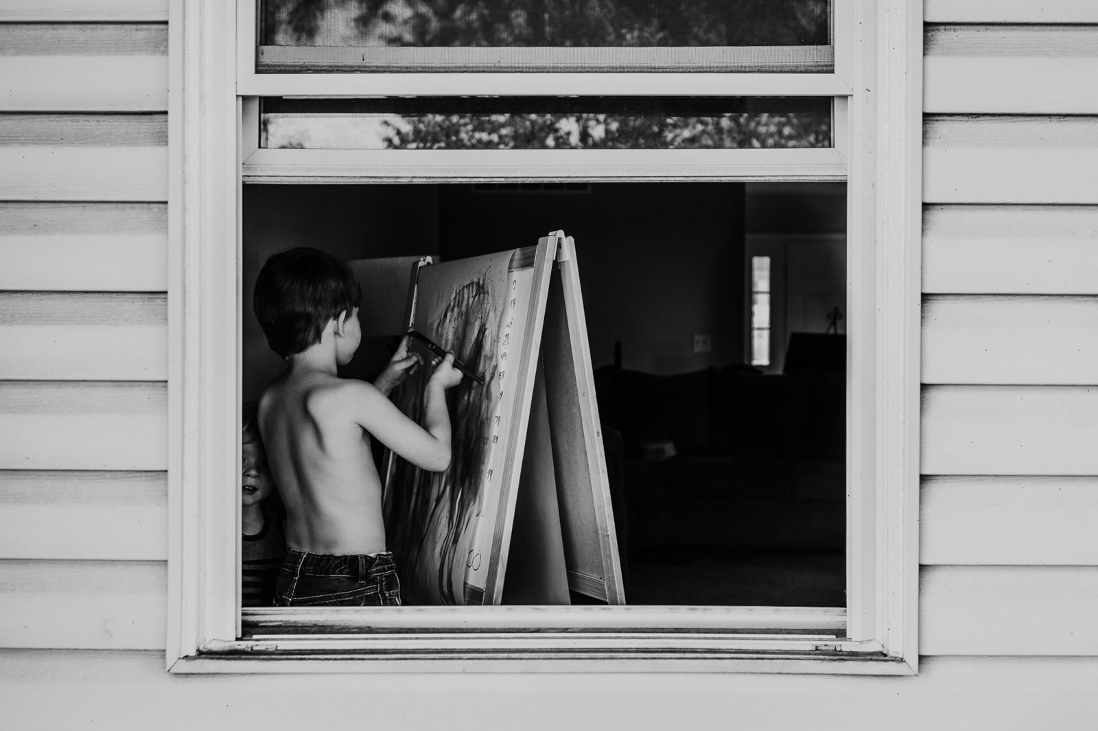 little boy painting in the window