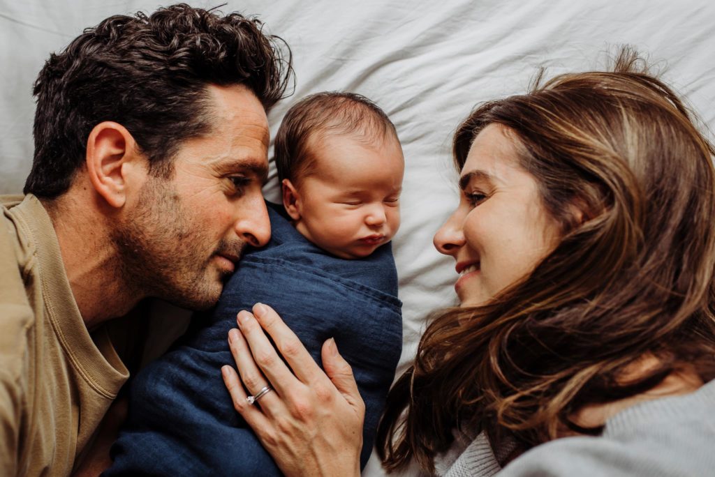 parents with baby posing for newborn photographer