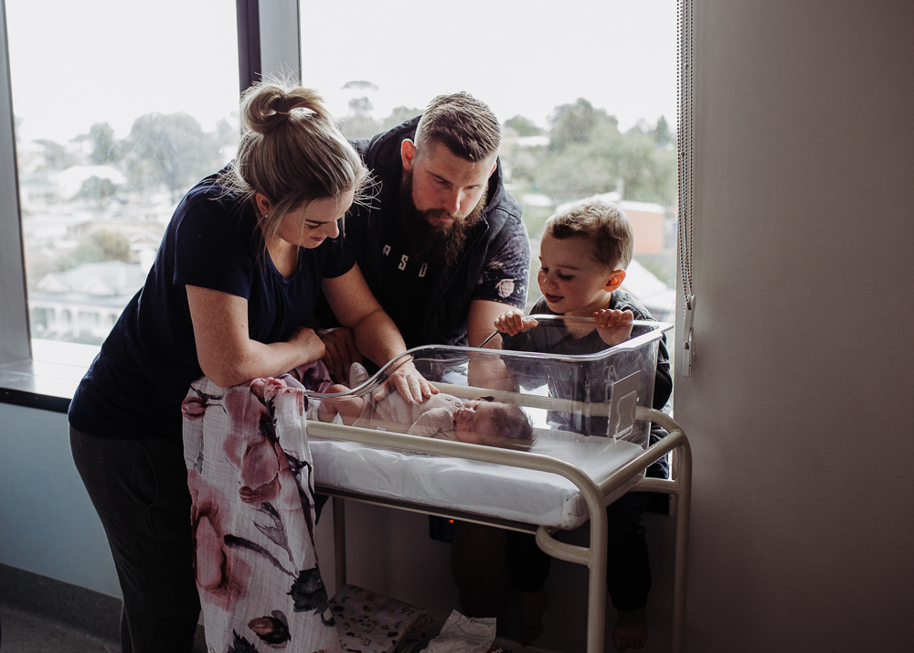  parents and son looking at newborn baby