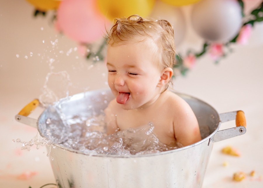 happy baby in metal bucket during cake smash photoshoot