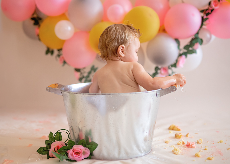 baby sitting in metal bucket after cake smash photos