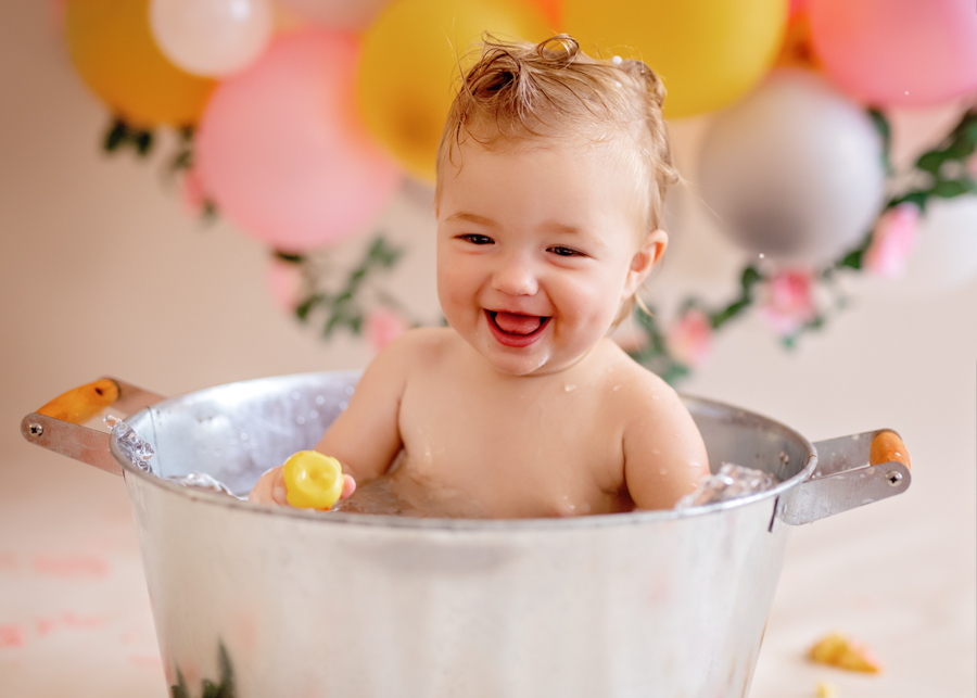laughing baby in bucket in cake smash photo 