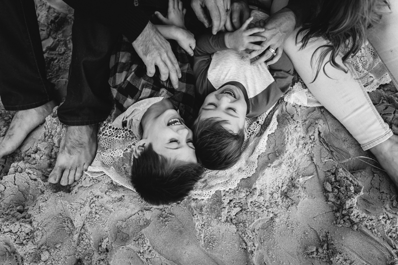 natural light shot of boys laughing lying on sand