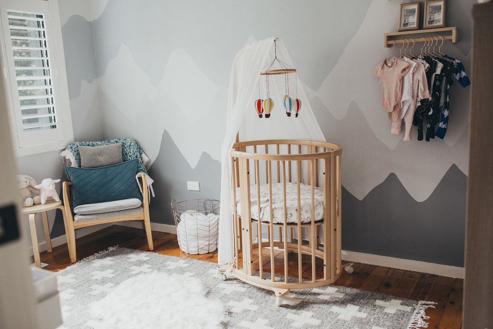 newborn baby nursery with grey walls and rug