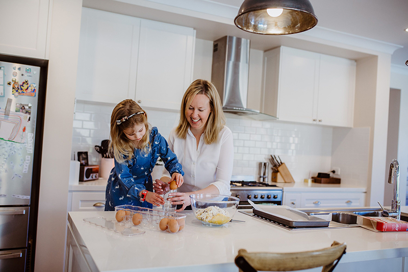 photography of mother and daughter cooking together