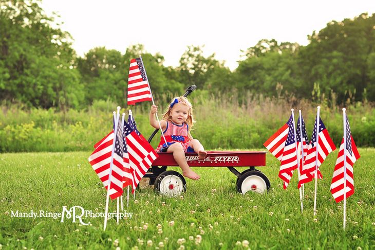4th of july pics of little girl in the yard surrounded by us flags