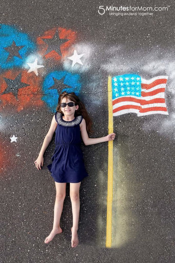 4th of july pic of girl laying on asphalt, holding american flag