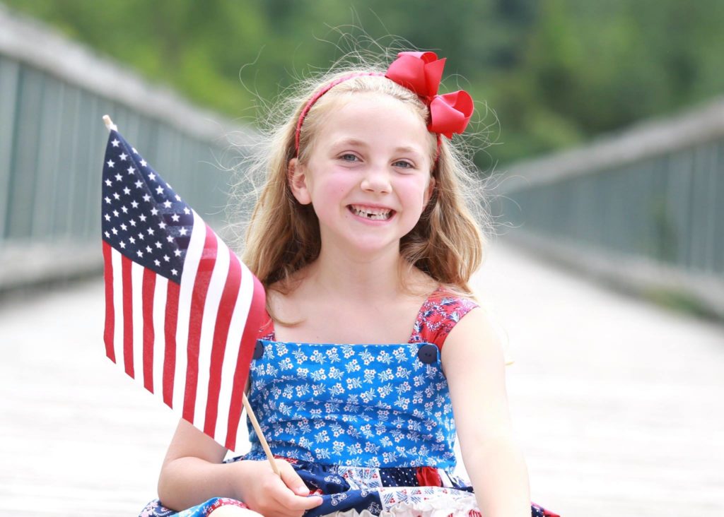 4th of july picture of girl holding the us flag in her hand