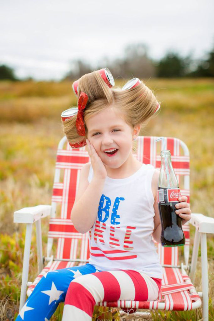 little girl dressed up in us flag holding a coca-cola