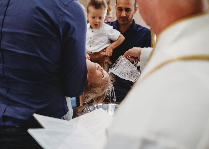 baptism photography of priest pouring water on baby’s head