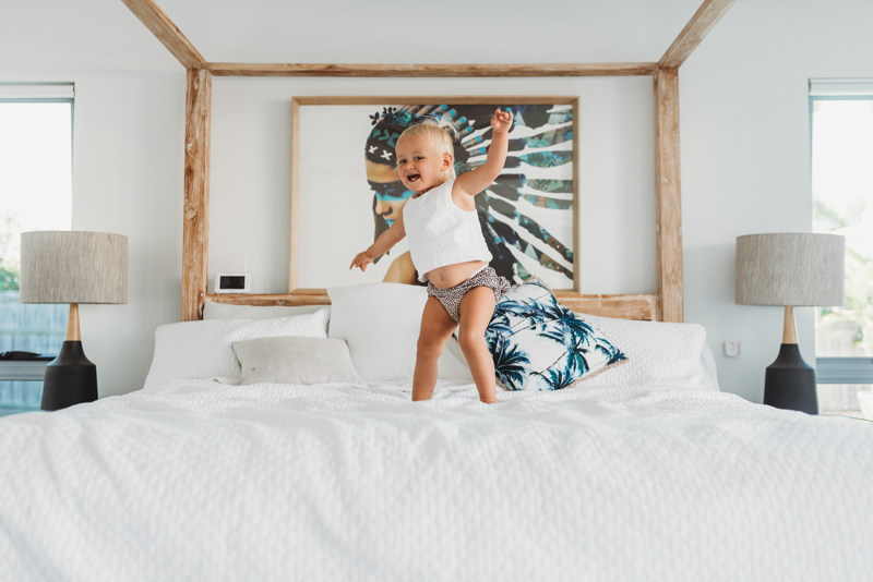maternity shoot with toddler jumping on bed