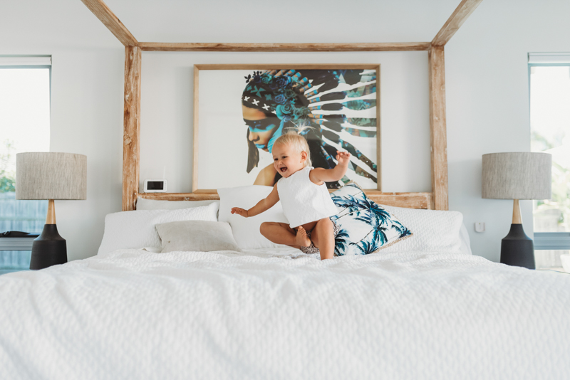 maternity photos with toddler while jumping on bed