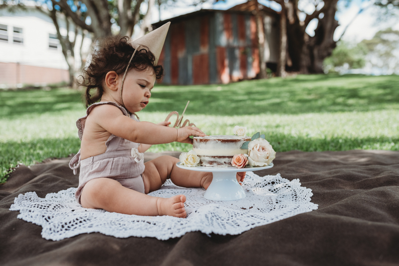 little girl playing with cake outdoors