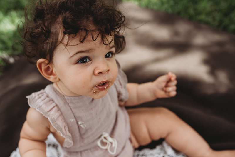 outdoor portrait of baby girl with cake in her face