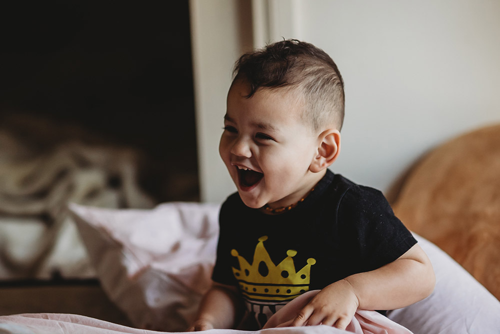 toddler boy laughing in low light