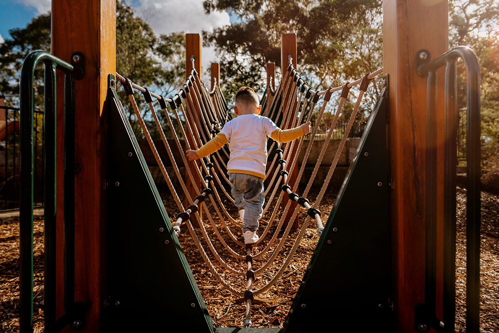Toddler boy on rope bridge in playground