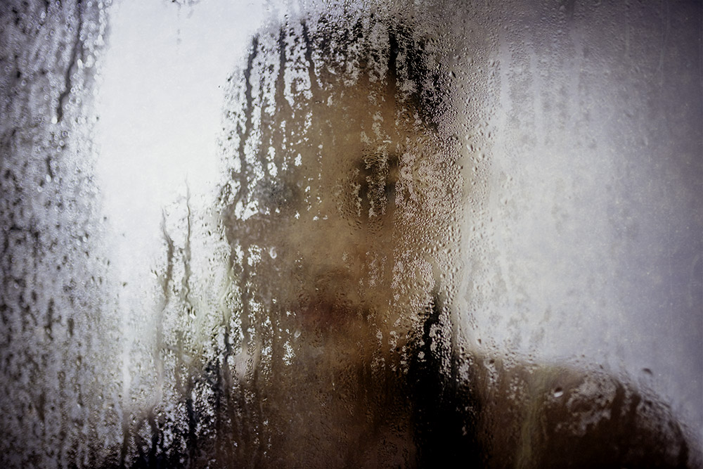 teenage girl behind foggy glass