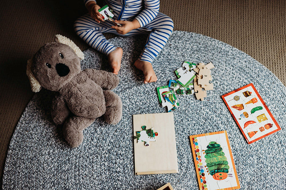faceless portrait of toddler with puzzles and stuffed koala