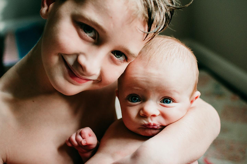 natural light closeup photograph of baby with brother 