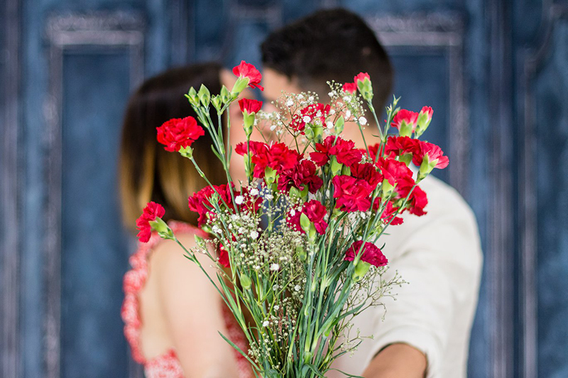 couple kissing behind a close up rose bouquet