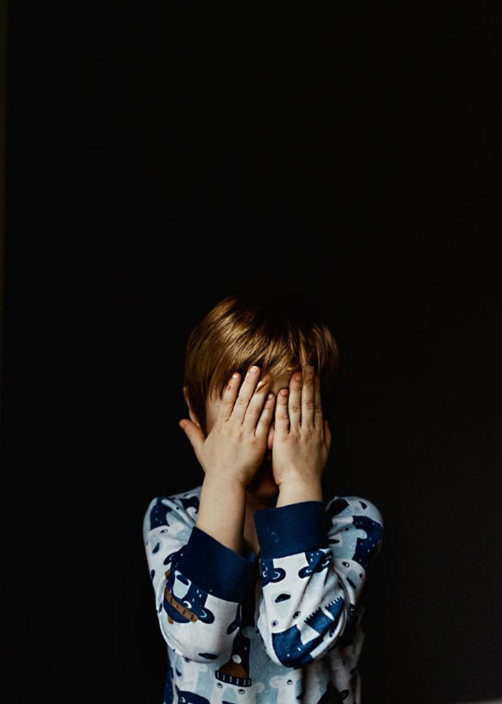 boy wearing pajamas in front of black background
