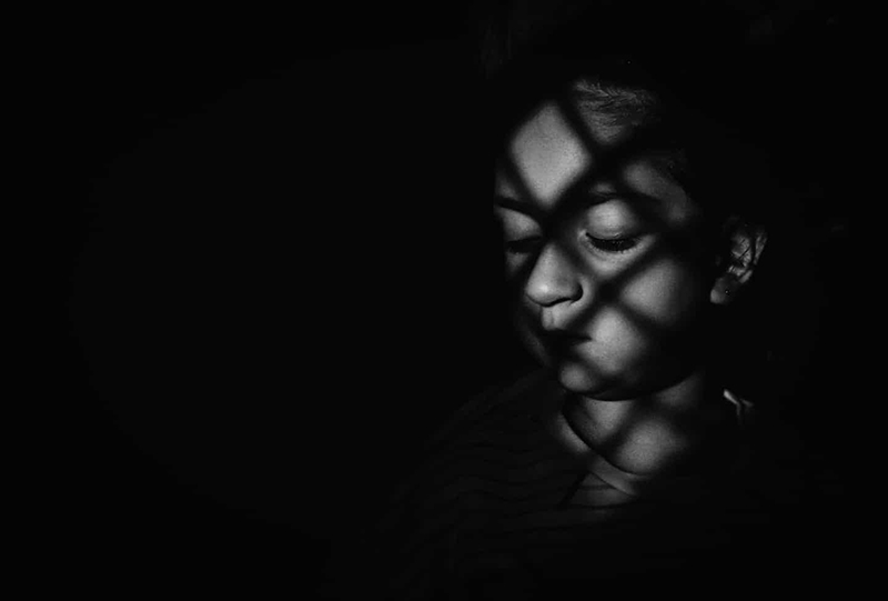 dark and moody monochrome photo of a girl with shadows on her face